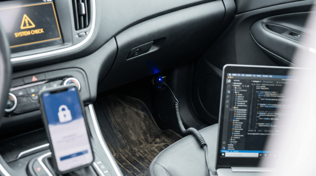 פנים של רכב מודרני עם מיקוד באזור שקע ה-OBD, תוך הדגשה עדינה של מערכות האלקטרוניקה ברכב. תאורה ניטרלית, סביבה מציאותית. המחשה של שיטות מתקדמות לגניבת רכב וסיכוני אבטחה דיגיטליים. צילום עריכתי איכותי, מציאותי ומאופק.