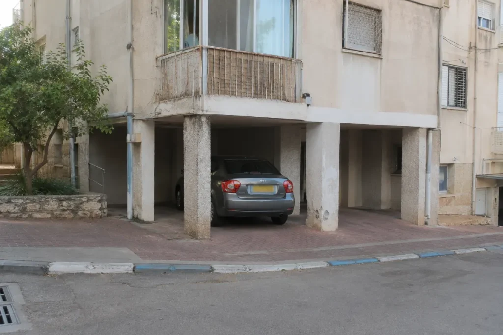 מכונית אפורה עומדת בחניה מקורה ליד עמודים
