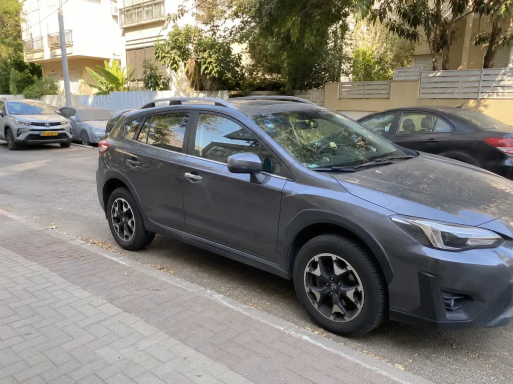 רכב אפור חונה ברחוב עירוני מוצל בישראל