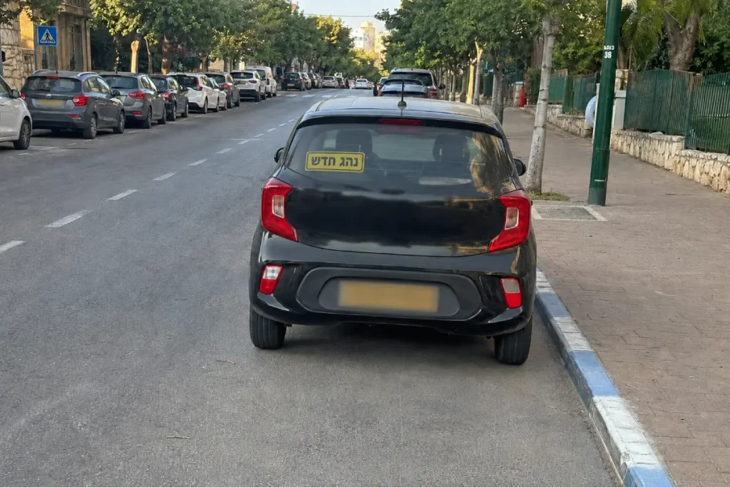 מכונית שחורה ברחוב עם מדבקת נהג חדש