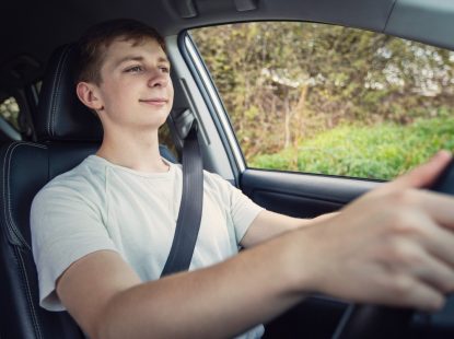 נהג צעיר עם חולצה לבנה נוהג ברכב